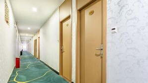 Een hotelgang met deuren met de nummers 506 en 507, voorzien van vloerbedekking en een behang met patroon.