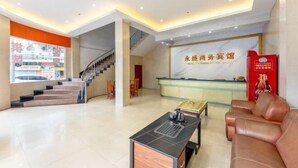 Een hotel lobby met een receptiebalie, een trap en een zithoek.