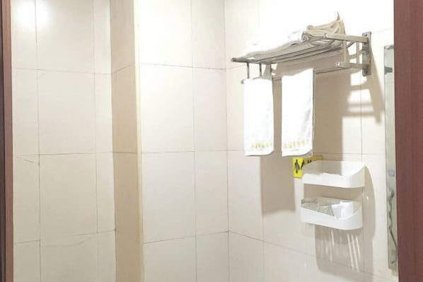 A bathroom with white tiled walls, a towel rack with two white towels, and a small sink with a trash bin. - Yongsheng Business Hotel (Jiangmen)