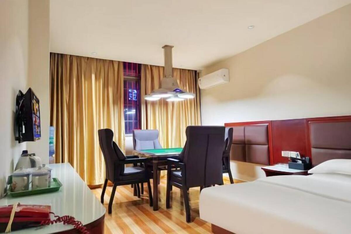 Hotelkamer met een bed, een bureau met telefoon, een tafel met stoelen en een pooltafel.