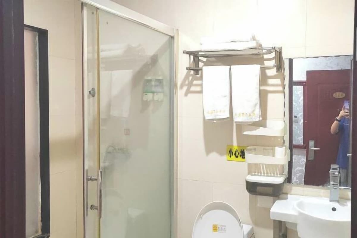 A bathroom with a glass shower door, a sink, and a towel rack with towels.