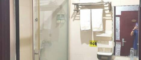 A bathroom with a glass shower door, a sink, and a towel rack with towels.