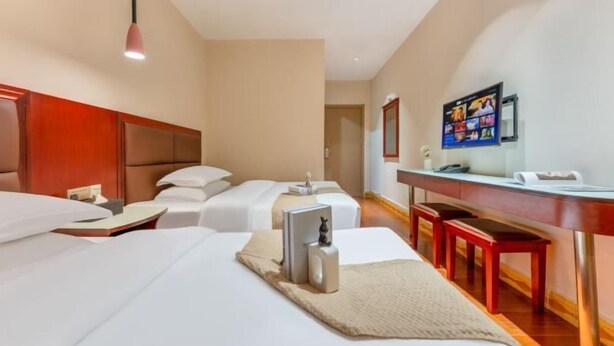Een hotelkamer met een bed, nachtkastjes, een bureau en een televisie.