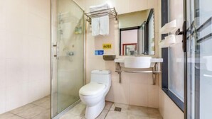 Een moderne badkamer met een douchecabine van glas, een toilet, een wastafel en een spiegel.