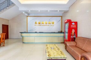 A reception area with a reception desk, a red vending machine, a sofa, and a patterned coffee table.