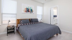 A bedroom with a bed, a nightstand, a ceiling fan, and a cityscape painting. - Austin Home · Corporate Spacious Luxury Housing (Austin)