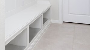 A hallway with a white bench, a door, and built-in shelving. - Austin Home · Corporate Spacious Luxury Housing (Austin)