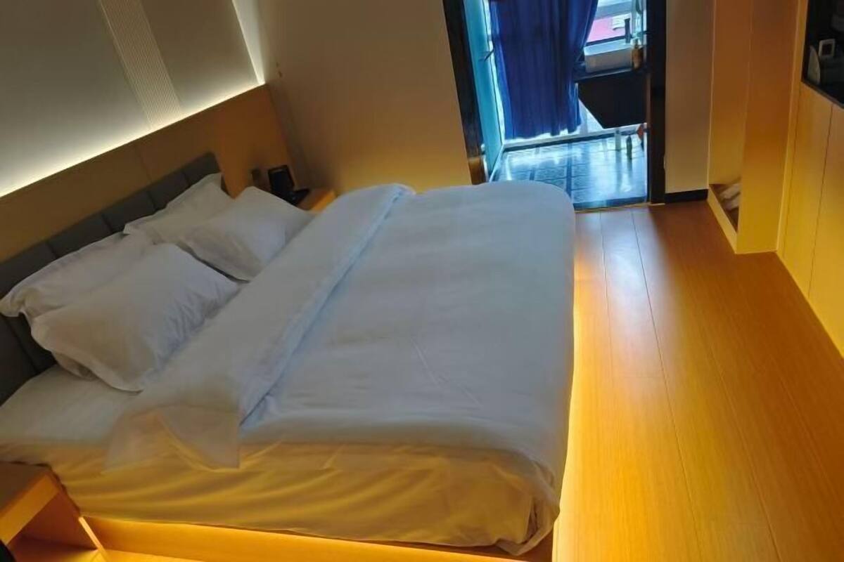 Ein Hotelzimmer mit Bett, Nachttisch und Blick nach draußen.