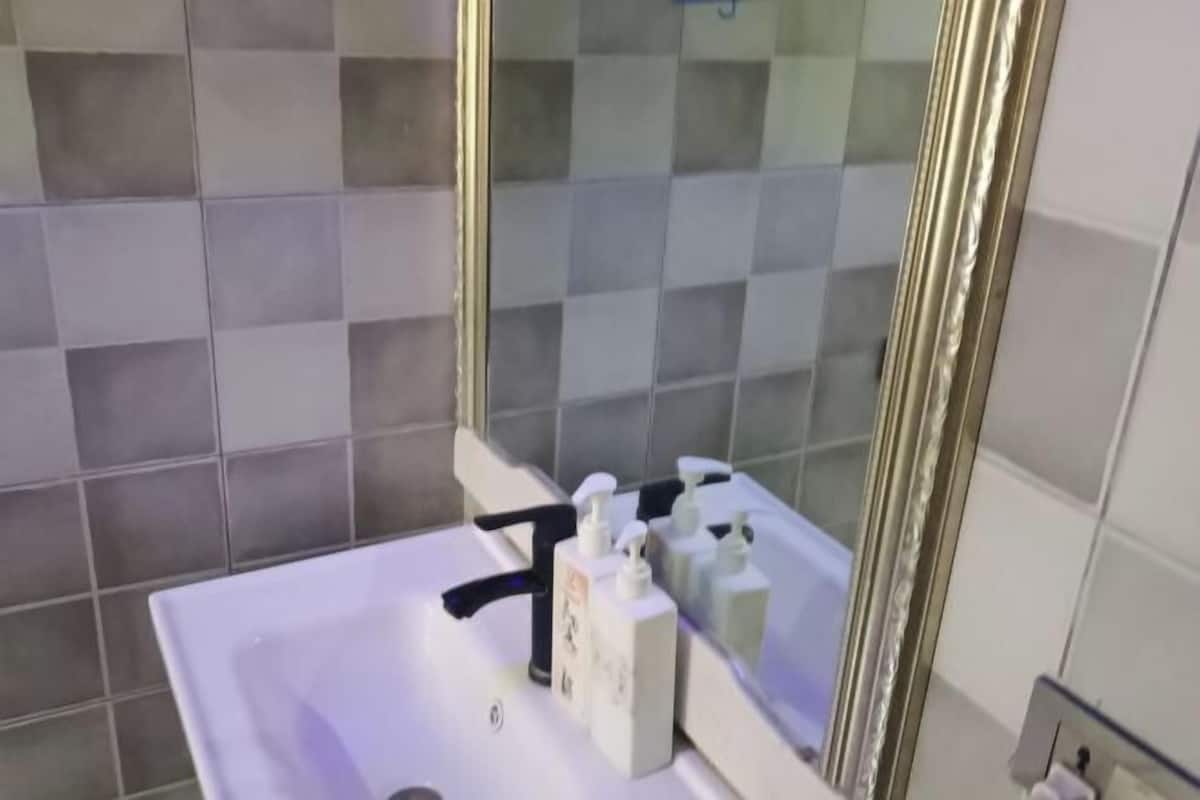 Ein Badezimmer mit einem weißen Waschbecken, einem Spiegel und einer gefliesten Wand.