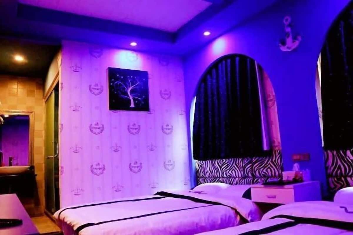 Ein Zimmer mit Bett, Nachttisch und einem fenster mit Vorhängen.