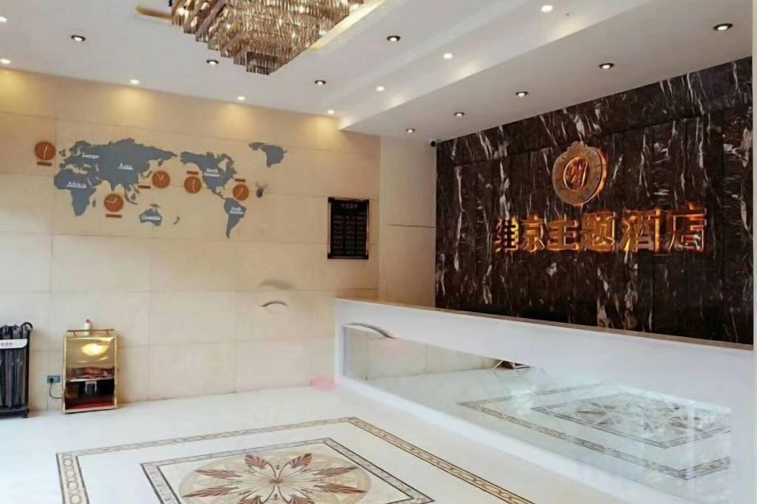 A hotel reception area with a world map, a reception desk, and a marble wall with hotel signage.