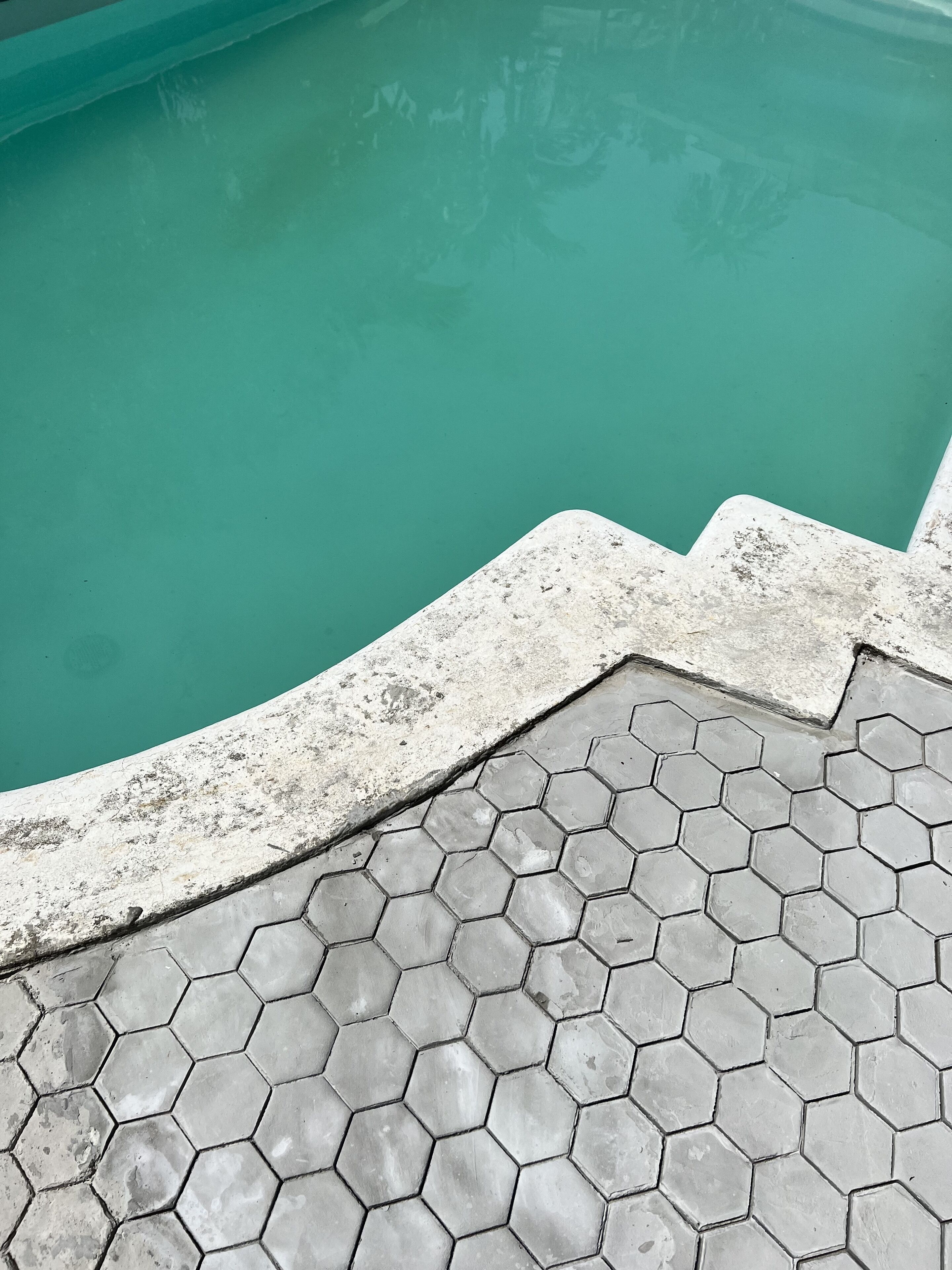 Un espace aménagé au bord de la piscine, avec un motif de carreaux hexagonaux et une bordure en béton.