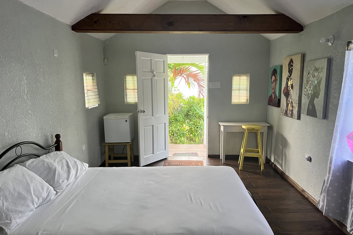A bedroom with a bed, a desk, and a door leading to a balcony.