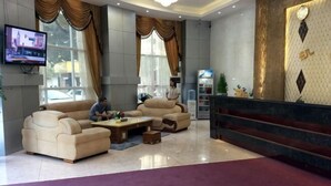 Eine Hotelhalle mit einer Rezeption, Sofas, einem Couchtisch und einem Fernseher.