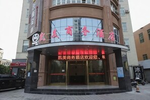 L’entrée d’un hôtel, avec une façade incurvée, des portes en verre et une enseigne aux lettres rouges.
