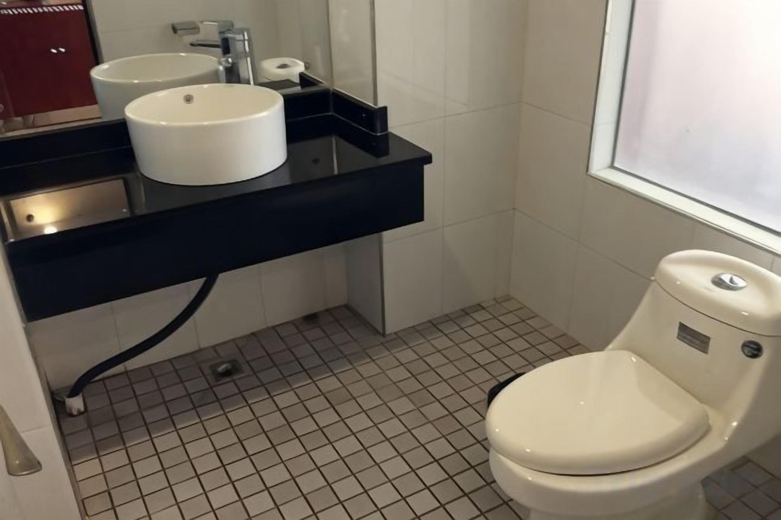 Ein Badezimmer mit einem weißen Waschbecken, einer Toilette und einem Spiegel über dem Waschbecken.
