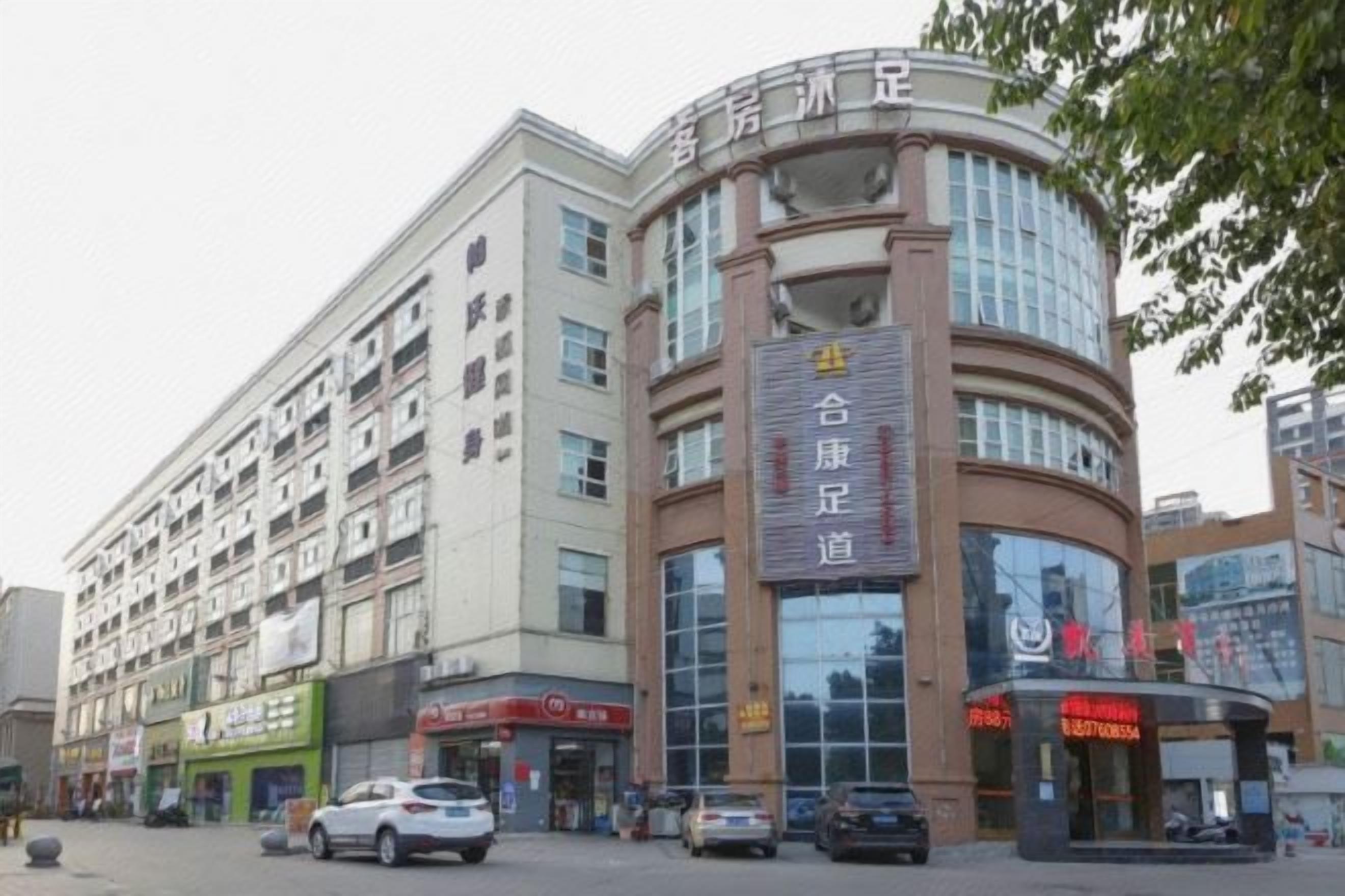 A multi-story building with a curved facade, a large glass entrance, and signage indicating a restaurant.