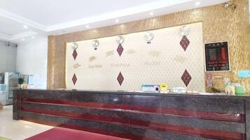 Un mostrador de recepción con encimera de mármol, alfombra roja y una pared con diseño decorativo y texto.