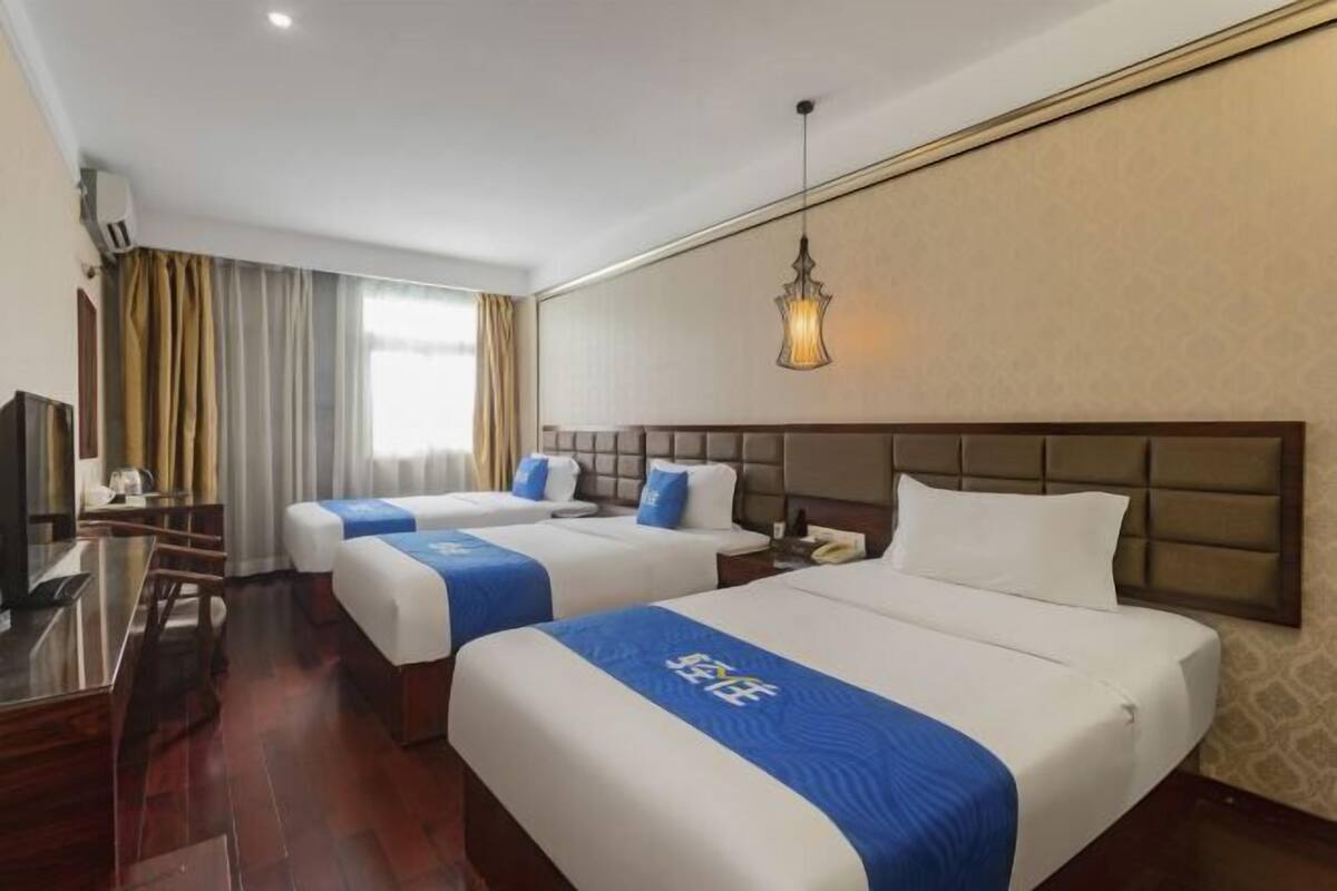 Habitación de hotel con dos camas, un escritorio y un televisor.