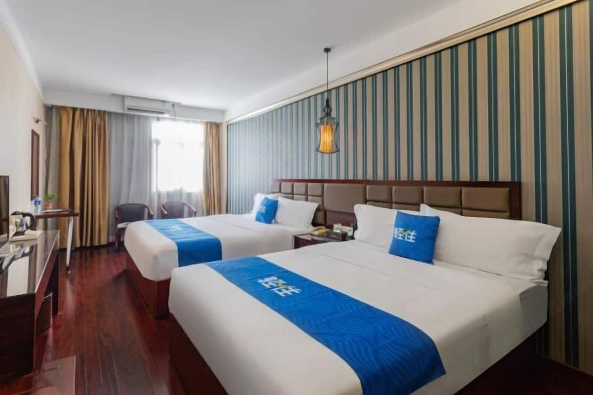 Habitación de hotel con dos camas, un escritorio y una silla.