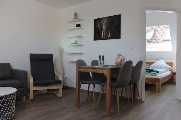 Un salon moderne comprenant un coin repas, un canapé, un fauteuil, une table et un lit.