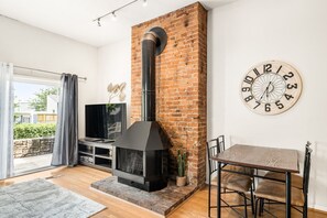 Una sala de estar moderna con chimenea de ladrillo, un televisor y un comedor.