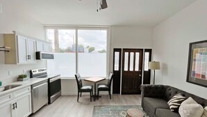 Un espacio habitable compacto con kitchenette, comedor y sofá.