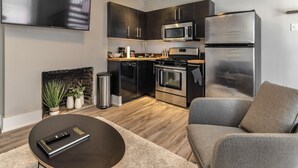 Une cuisine moderne avec des meubles de couleur sombre, des appareils en acier inoxydable et un téléviseur à écran plat fixé au-dessus du plan de travail.