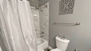Een badkamer met douche, toilet en een decoratief wandobject.