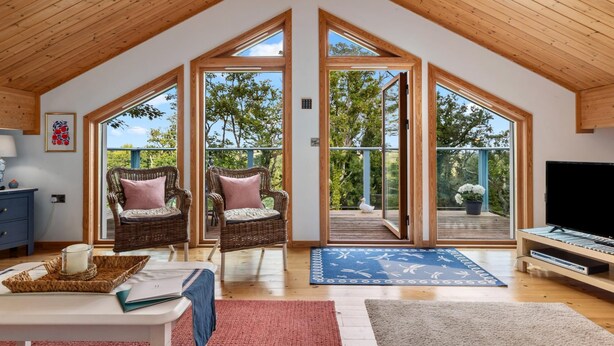 A spacious loft with high ceilings and large windows, offering views of the outdoors. - The Bluebell - Luxury Lodge With Hot Tub (Tenby)
