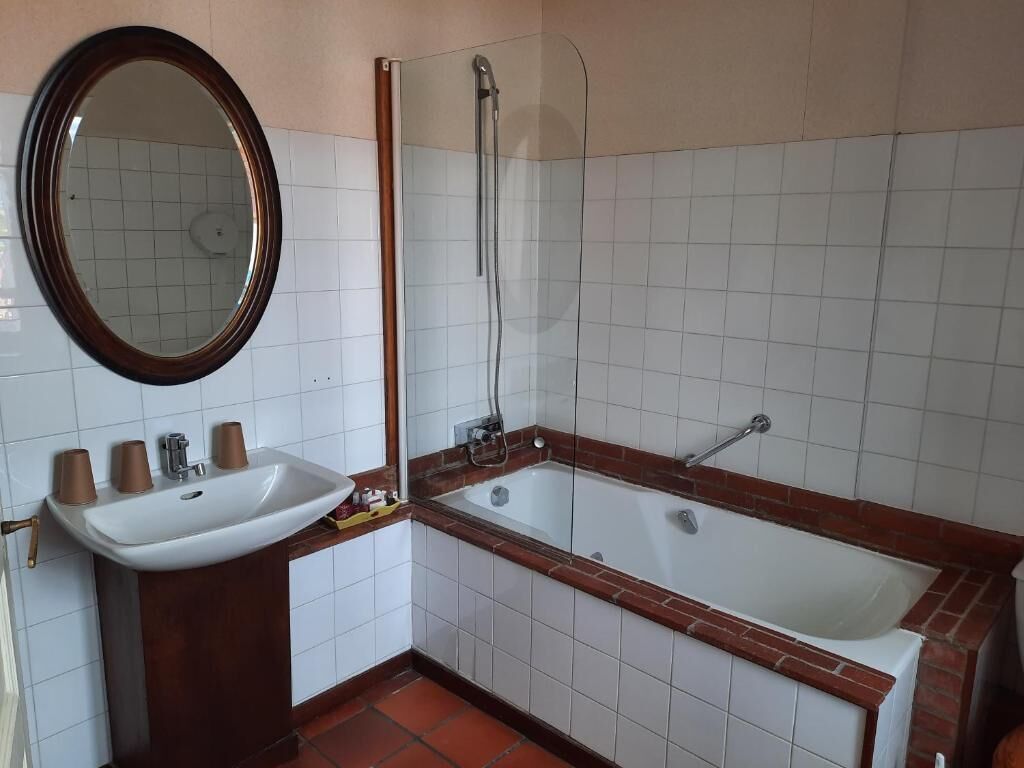 A bathroom with a white sink, mirror, and bathtub.