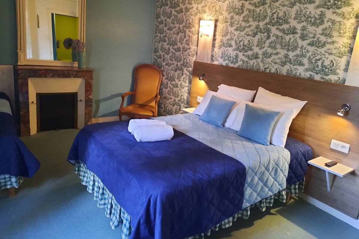 Ein Hotelzimmer mit einem großen Bett, einem Sessel, einem Nachttisch und einem Spiegel.