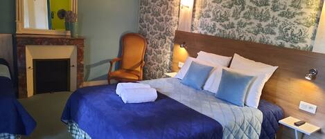 A hotel room with a large bed, a chair, a nightstand, and a mirror.