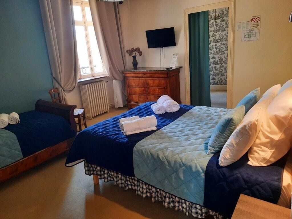 A hotel room with two beds, a wooden dresser, a flat-screen TV, and a window with curtains.
