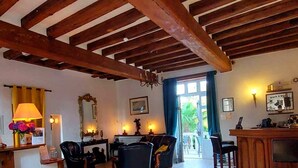 A rustic interior with exposed wooden beams, a bar area, and a dining space with chairs and a table.