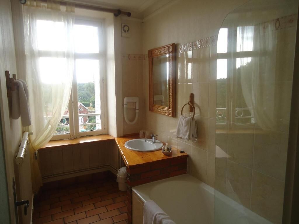 A bathroom with a wooden vanity, a white sink, a mirror, and a shower area.