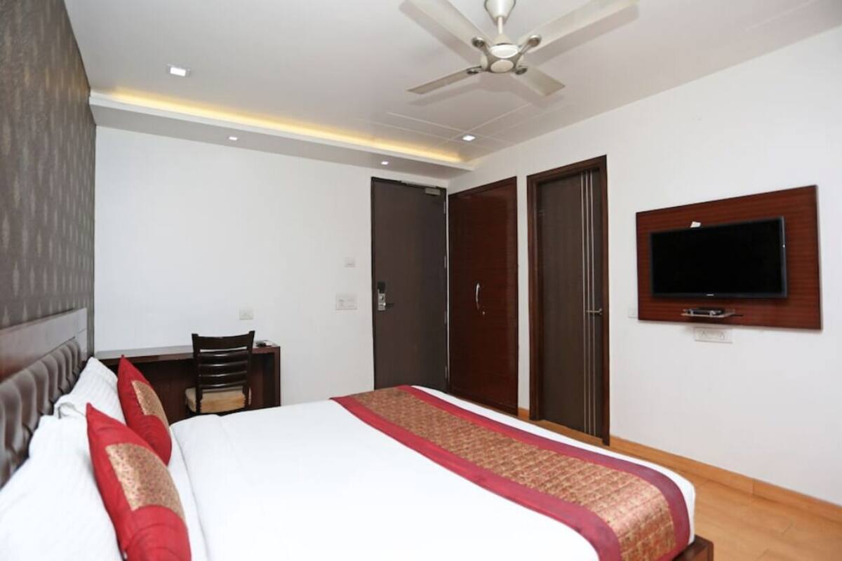 A hotel room with a bed, a desk, a chair, a television, and a wardrobe.