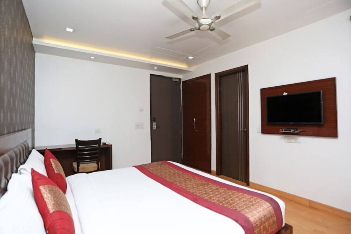 A hotel room with a bed, a desk, a chair, a TV, and a wardrobe.