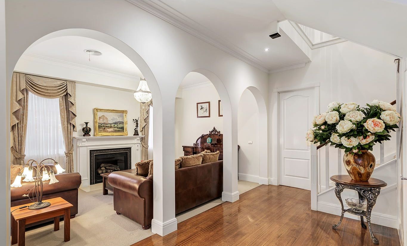 A spacious living room with a fireplace, a sofa, a coffee table, and a vase of flowers.