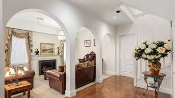 A spacious living room with a fireplace, a sofa, a coffee table, and a vase of flowers.