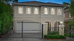 Une maison à deux étages avec un garage, une clôture en métal noir et une pelouse bien entretenue.