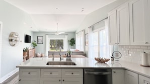 Cozinha moderna com ilha central, eletrodomésticos de aço inoxidável e vista para uma sala de estar.