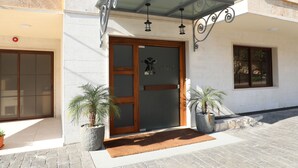 A building entrance with a glass door, potted plants, and a stone-paved area. - byblos palms hotel (Blat)