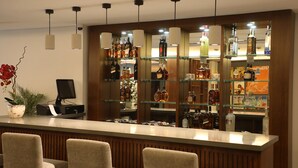 A bar area with a counter, multiple shelves of liquor bottles, and two upholstered chairs. - byblos palms hotel (Blat)