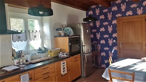 Keittiössä on puukuvioiset kaapit, ruostumattomasta teräksestä valmistettu jääkaappi ja kuviollinen tapetti.