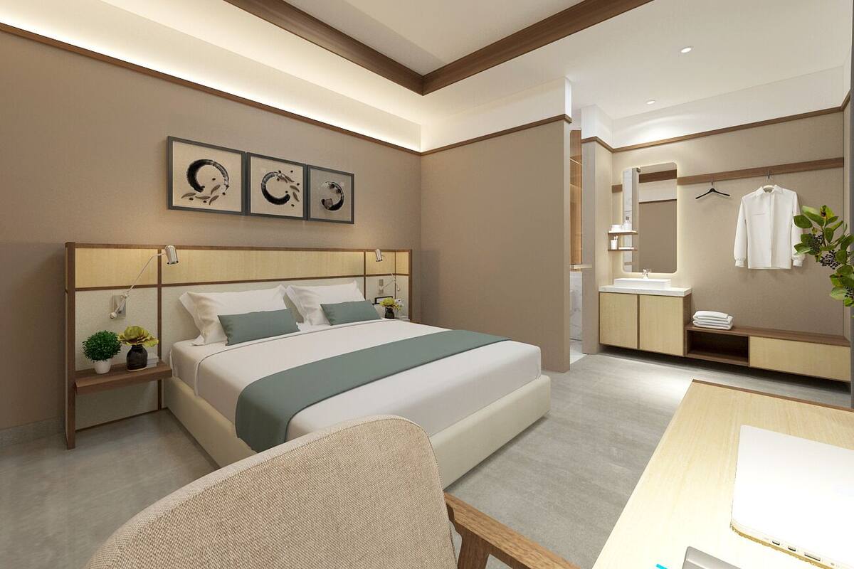 Ett modernt hotellrum med en stor säng, sängbord, ett skrivbord och ett badrum med spegel och handduksställ.