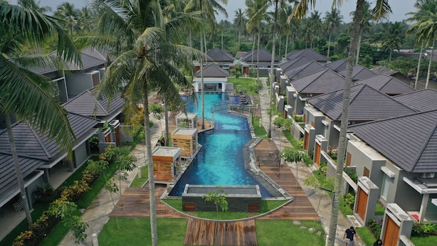 Un complexe hôtelier comprenant plusieurs villas, une piscine centrale et une végétation luxuriante.