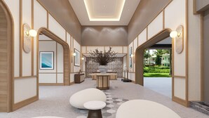 Un hall d’hôtel moderne doté d’un espace salon central, de tableaux décoratifs et offrant une vue sur le jardin extérieur.