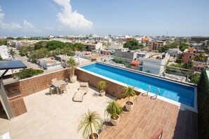 A rooftop pool with lounge chairs and potted plants, surrounded by city buildings. - Studio505 En Vanessa24 A 5min De La 5ta Av Y Playa (Playa del Carmen)