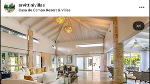 A spacious living room with a white sofa, a coffee table, and a chandelier. There are large windows and a view of the outdoors. - Snrvittinivillas Mng Spacius and Best Loc in Casa de Campo Resorts Gr8 Villa (La Romana)